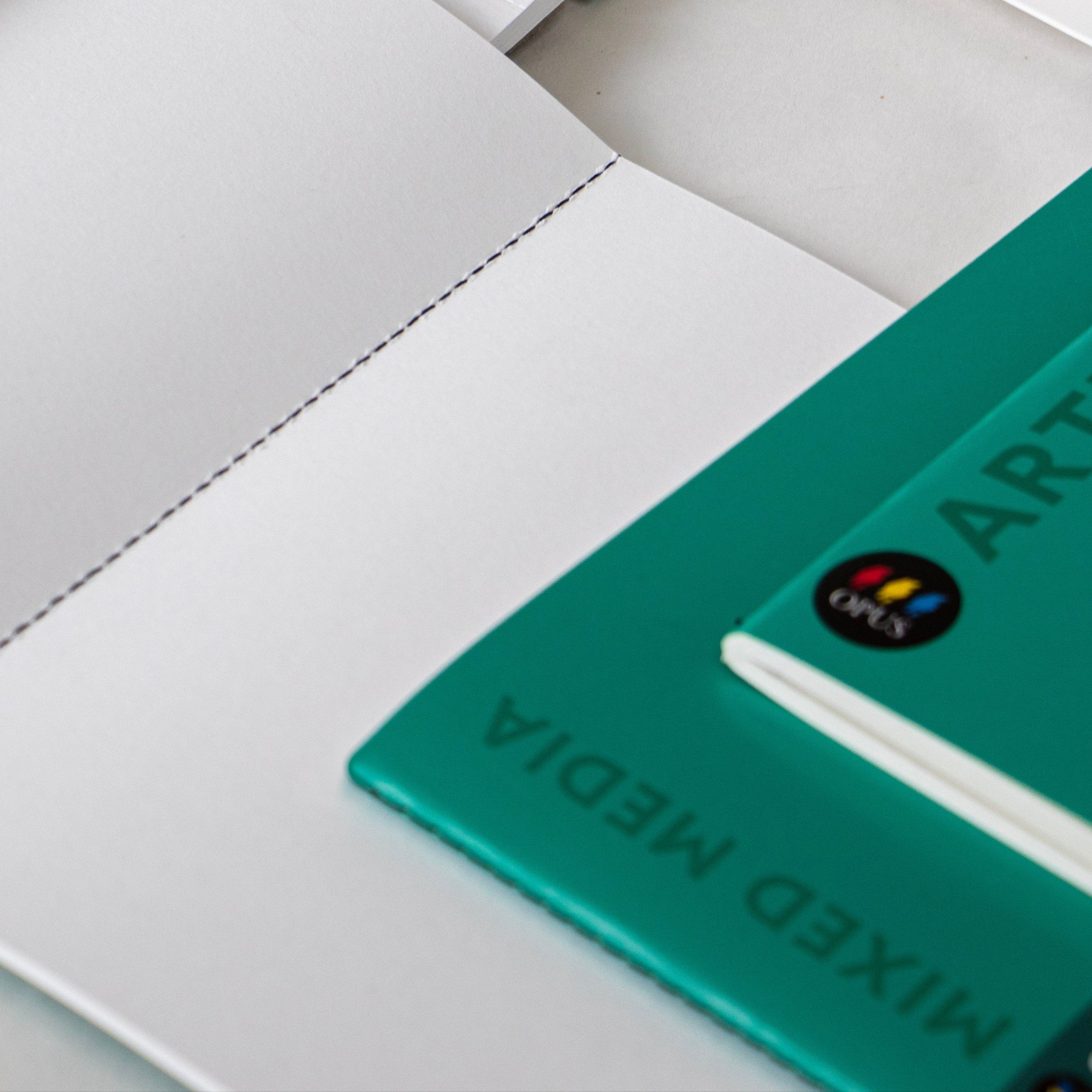 Set of art supply books with green covers on a white surface