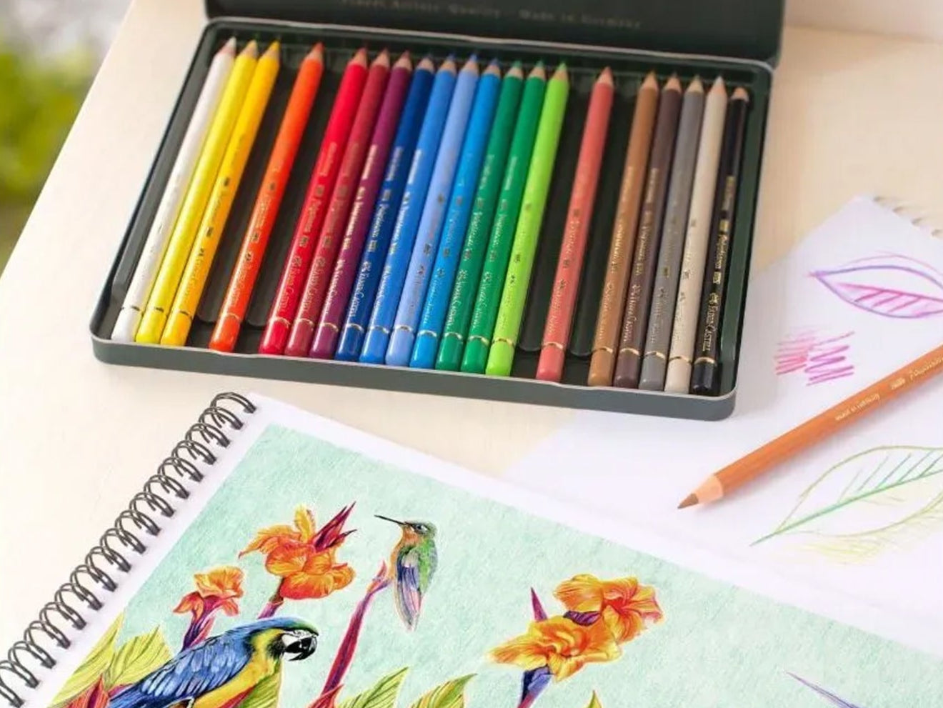 Coloring book with a colorful bird and floral design, surrounded by colored pencils.
